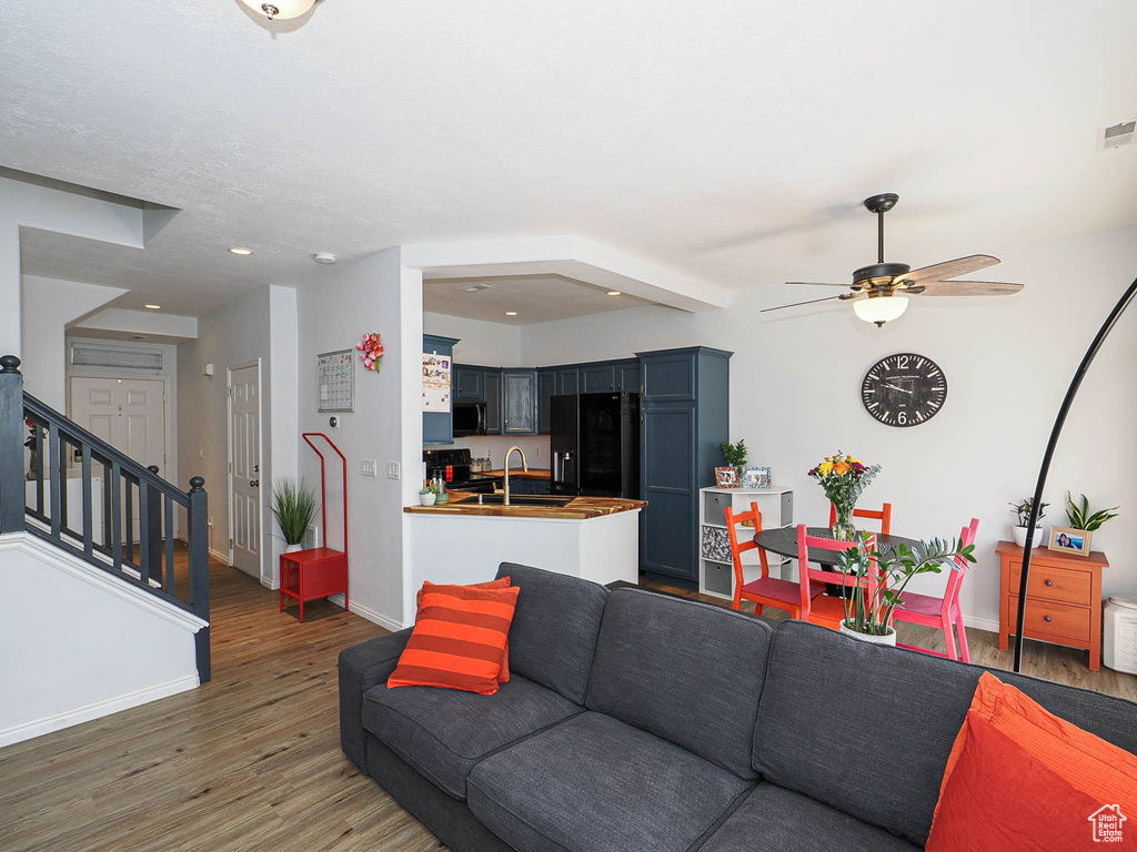 Living area featuring wood finished floors, ceiling fan, stairway, and recessed lighting