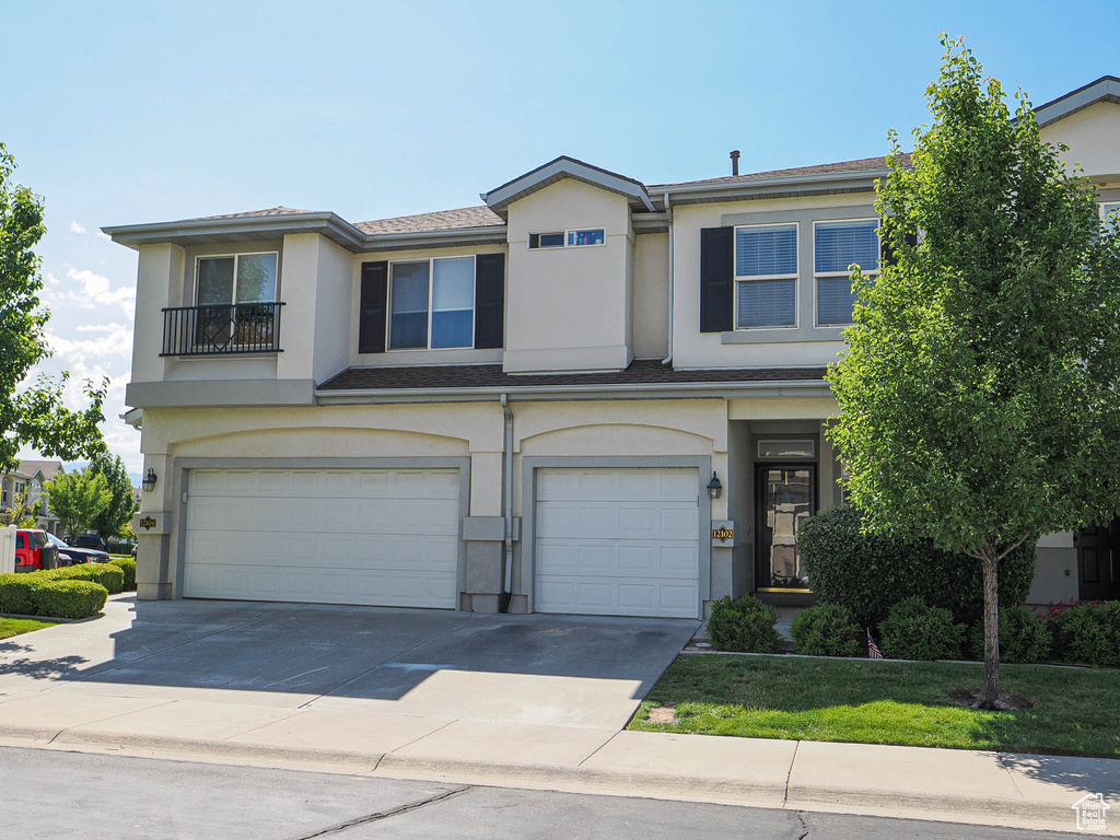 View of front facade featuring an attached garage, stucco siding, and concrete driveway