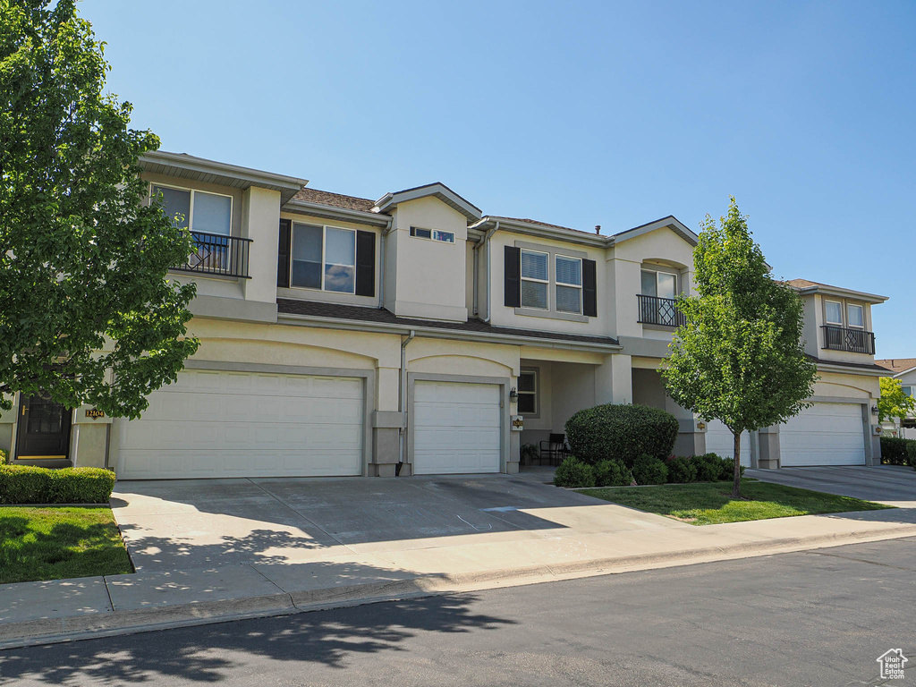 View of property with a garage, stucco siding, and concrete driveway