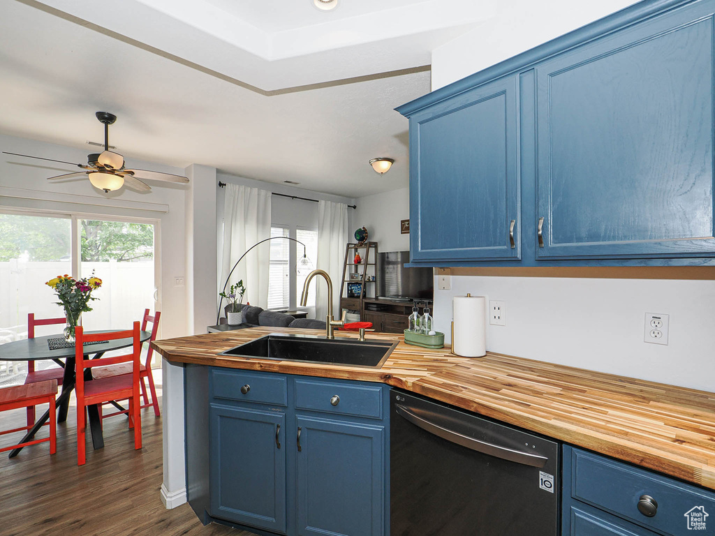 Kitchen with dishwashing machine, butcher block countertops, and blue cabinets