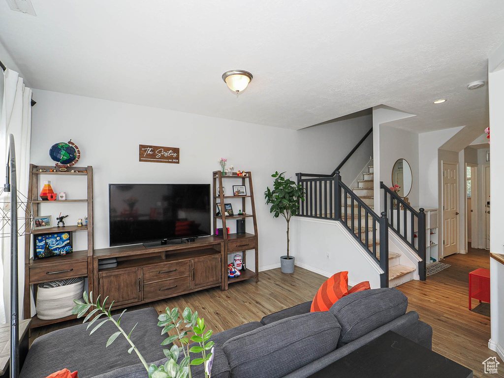 Living room featuring wood finished floors, stairway, and recessed lighting