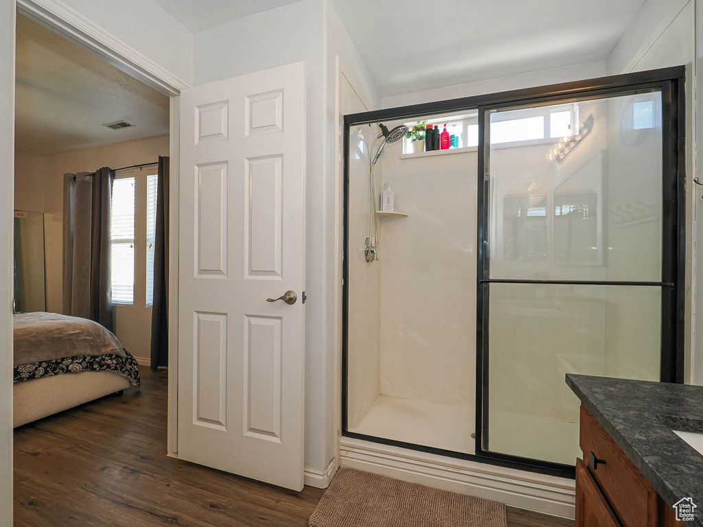 Bathroom featuring a stall shower, wood finished floors, vanity, and connected bathroom