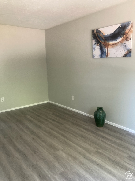 Unfurnished room with baseboards and dark wood-style flooring