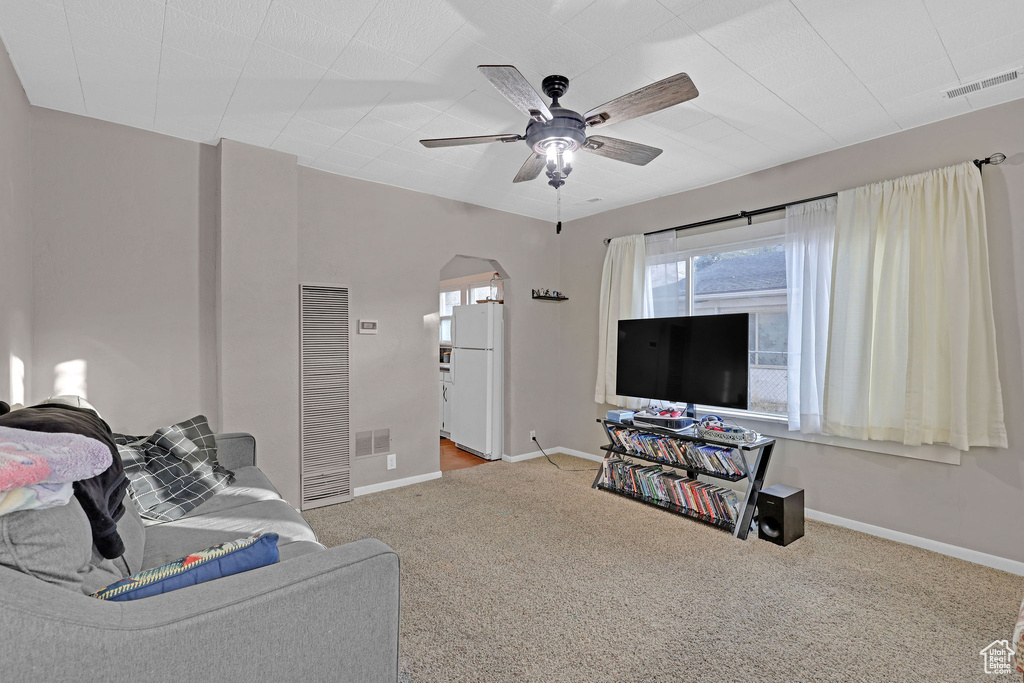 Carpeted living room with a heating unit, a ceiling fan, and arched walkways