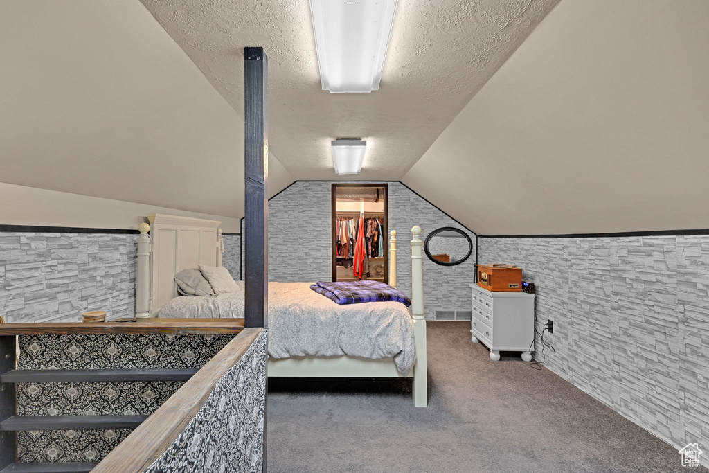 Carpeted bedroom with a textured ceiling and lofted ceiling