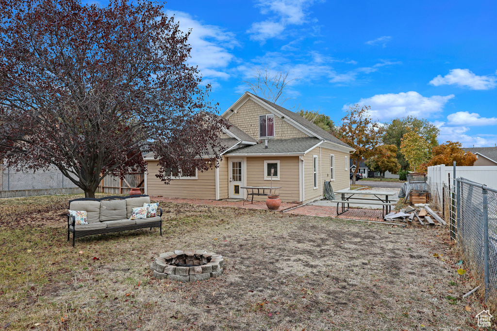 Rear view of house featuring an outdoor living space with a fire pit, a fenced backyard, and a patio area
