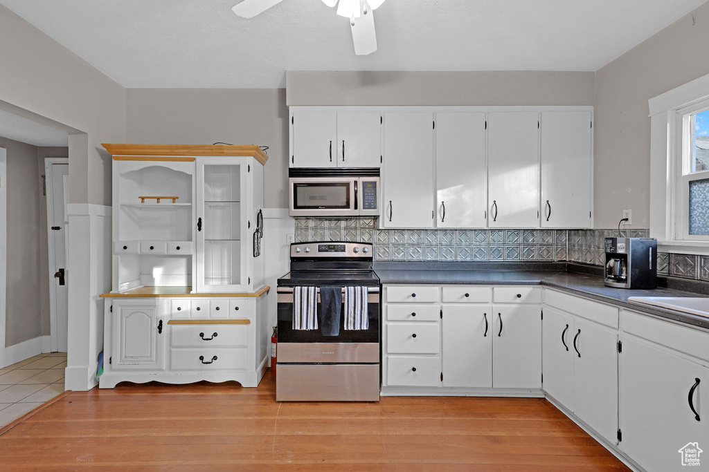 Kitchen featuring appliances with stainless steel finishes, dark countertops, tasteful backsplash, and white cabinetry