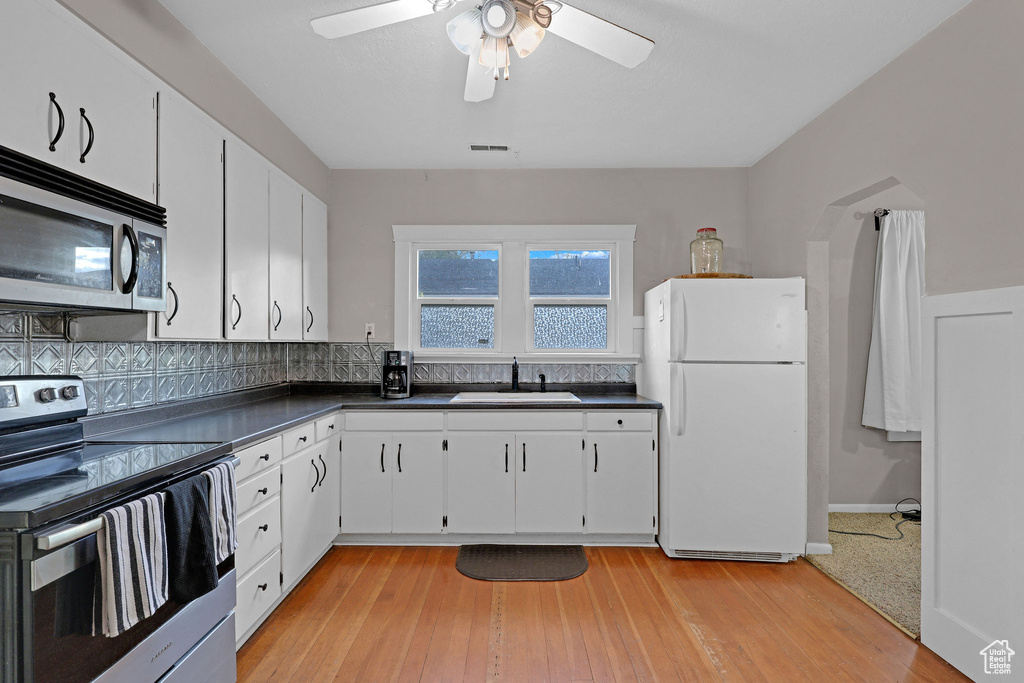 Kitchen with appliances with stainless steel finishes, dark countertops, ceiling fan, and white cabinetry