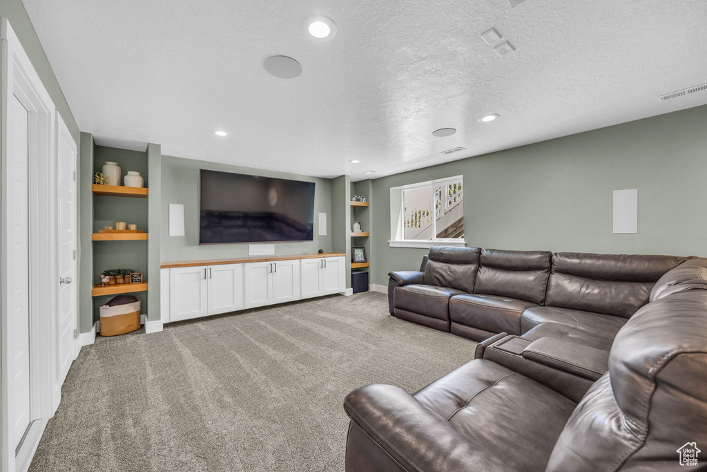Living area with light carpet, built in features, recessed lighting, and a textured ceiling