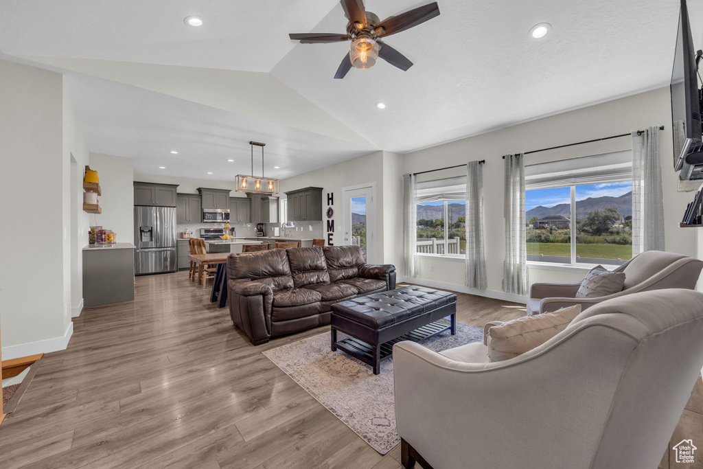 Living room with a ceiling fan, lofted ceiling, light wood-style floors, and recessed lighting