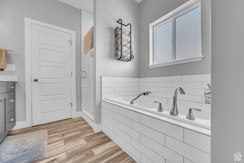 Bathroom with a bath, a shower stall, vanity, and wood finished floors