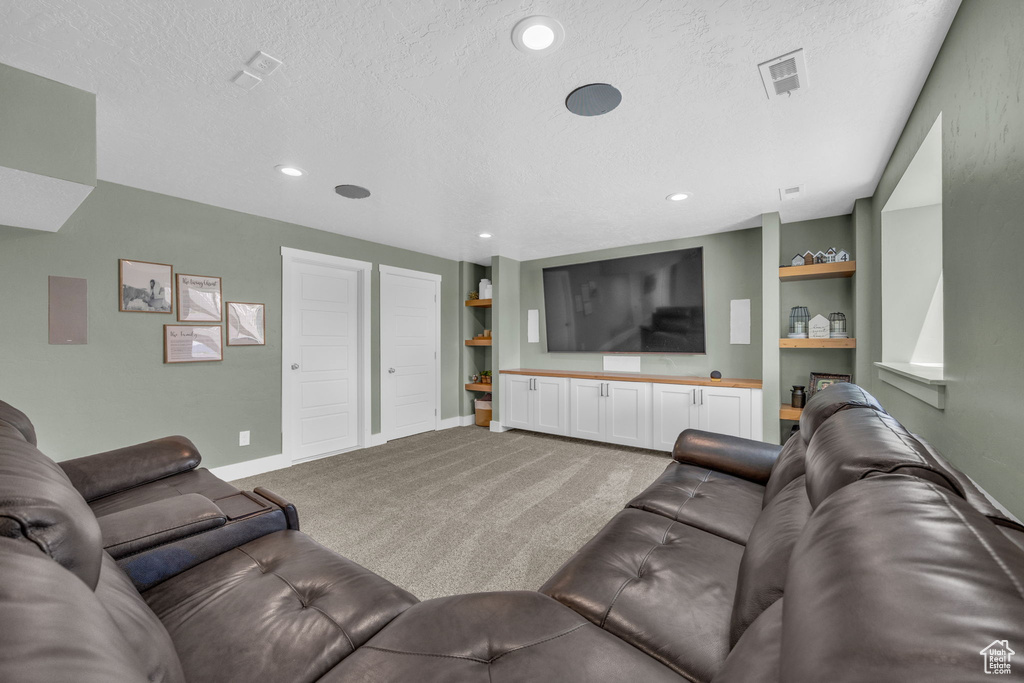 Carpeted living area featuring a textured ceiling, built in features, and recessed lighting