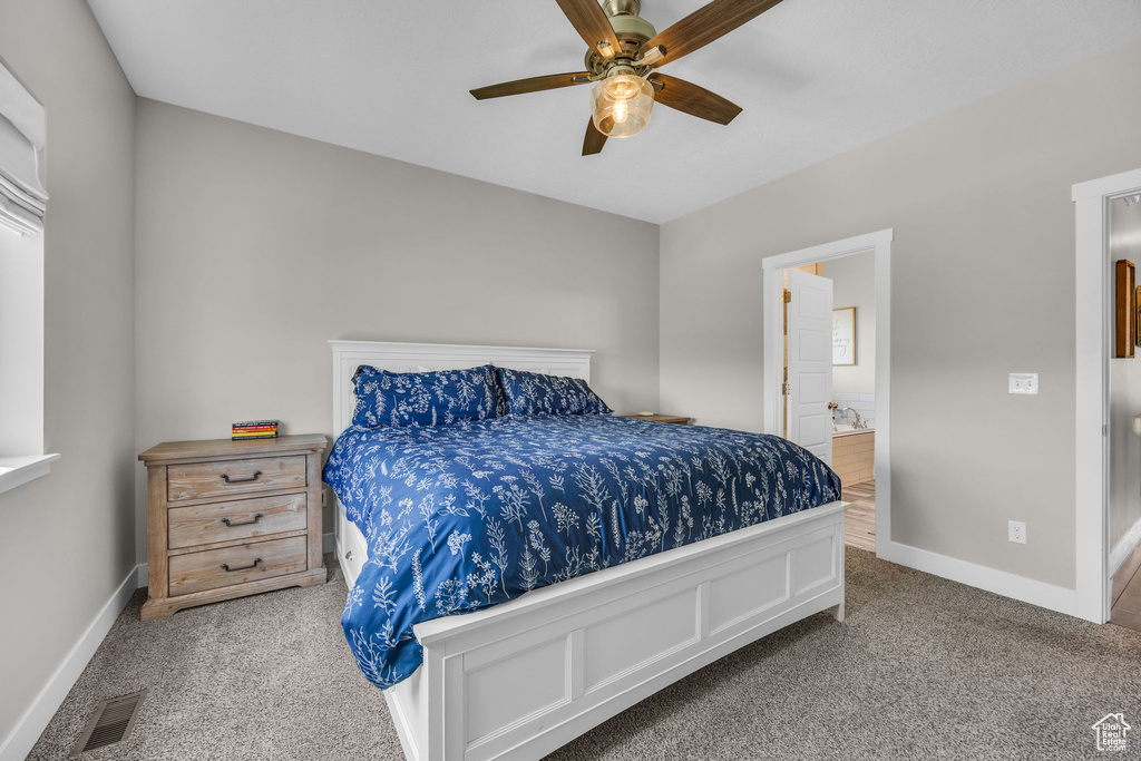 Carpeted bedroom featuring ensuite bathroom and a ceiling fan