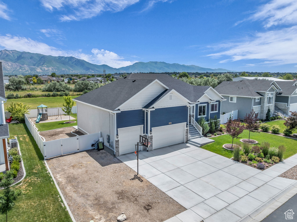 Single story home with a gate, concrete driveway, a garage, and a mountain view