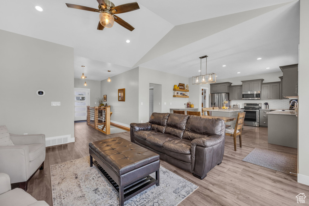 Living area with ceiling fan, light wood-style floors, lofted ceiling, and recessed lighting