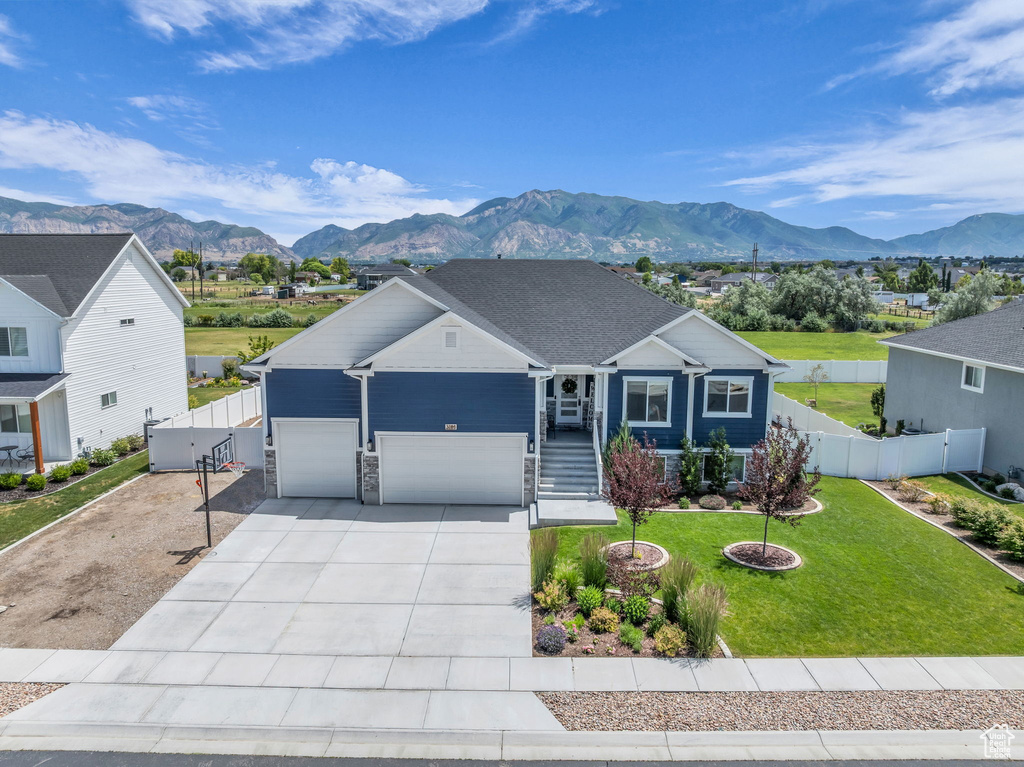 View of front of house with a gate, a mountain view, concrete driveway, an attached garage, and stone siding