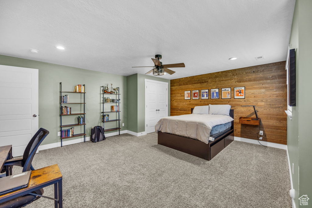Carpeted bedroom featuring wood walls, recessed lighting, a ceiling fan, and a closet