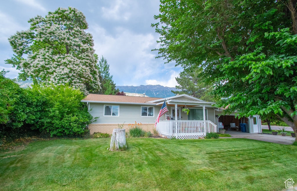 View of front of property featuring a porch, a front lawn, a mountain view, and a carport
