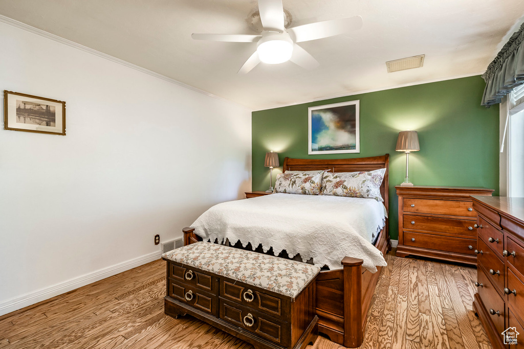 Bedroom with light wood finished floors, crown molding, and ceiling fan
