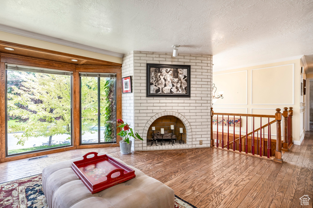 Living room featuring a textured ceiling, a fireplace, healthy amount of natural light, hardwood / wood-style floors, and a decorative wall