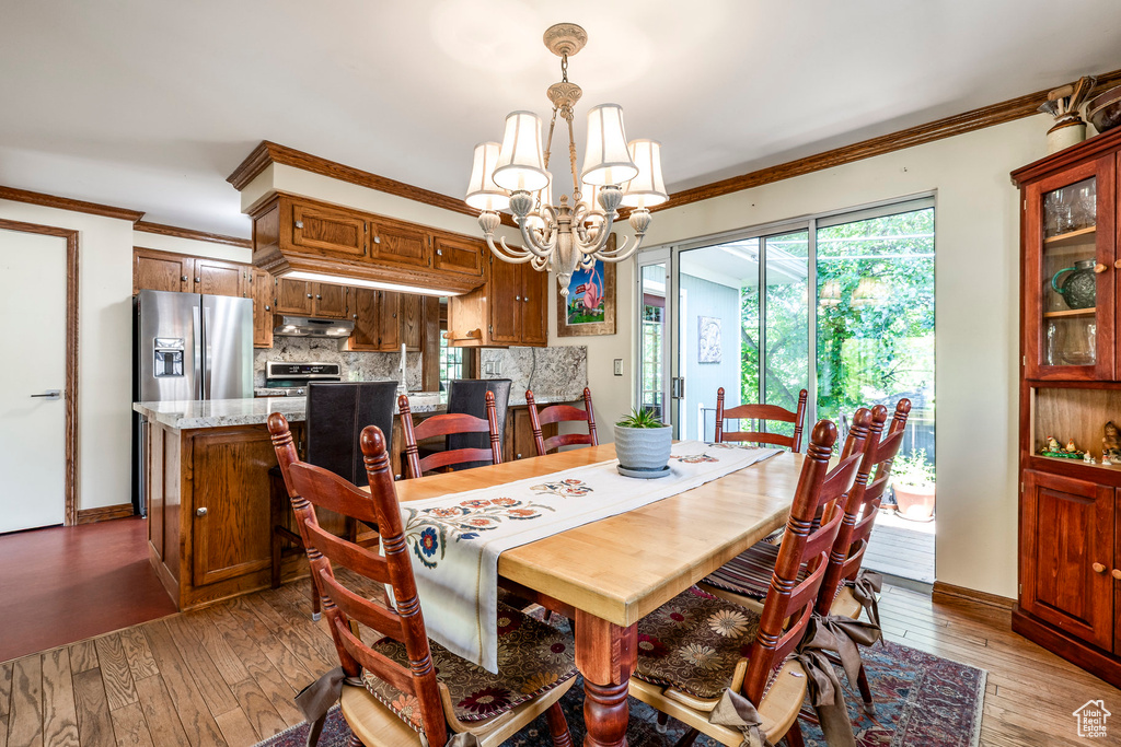 Dining space with a chandelier, crown molding, and wood-type flooring