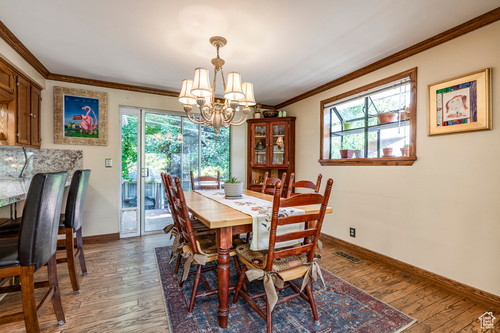 Dining room featuring crown molding, a chandelier, and wood finished floors