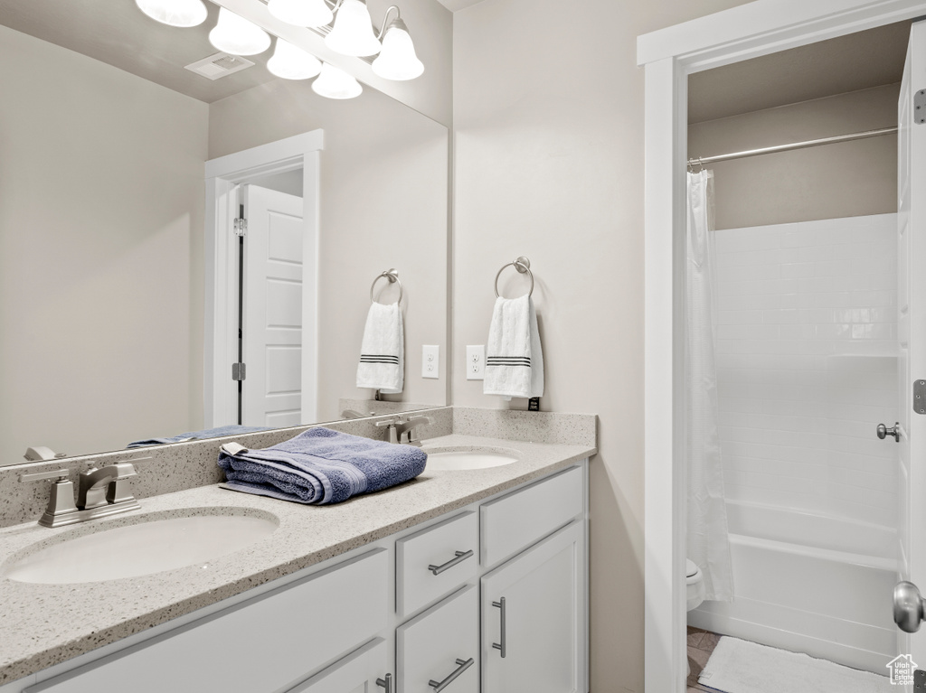 Full bathroom with double vanity and shower / bath combo with shower curtain
