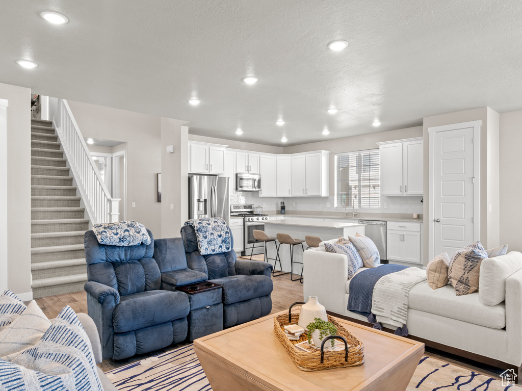 Living area with light wood-style flooring, stairway, and recessed lighting