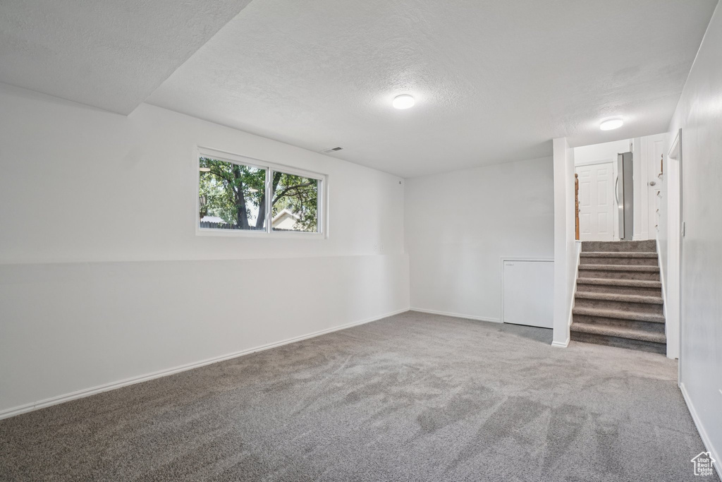 Carpeted spare room with a textured ceiling and stairway