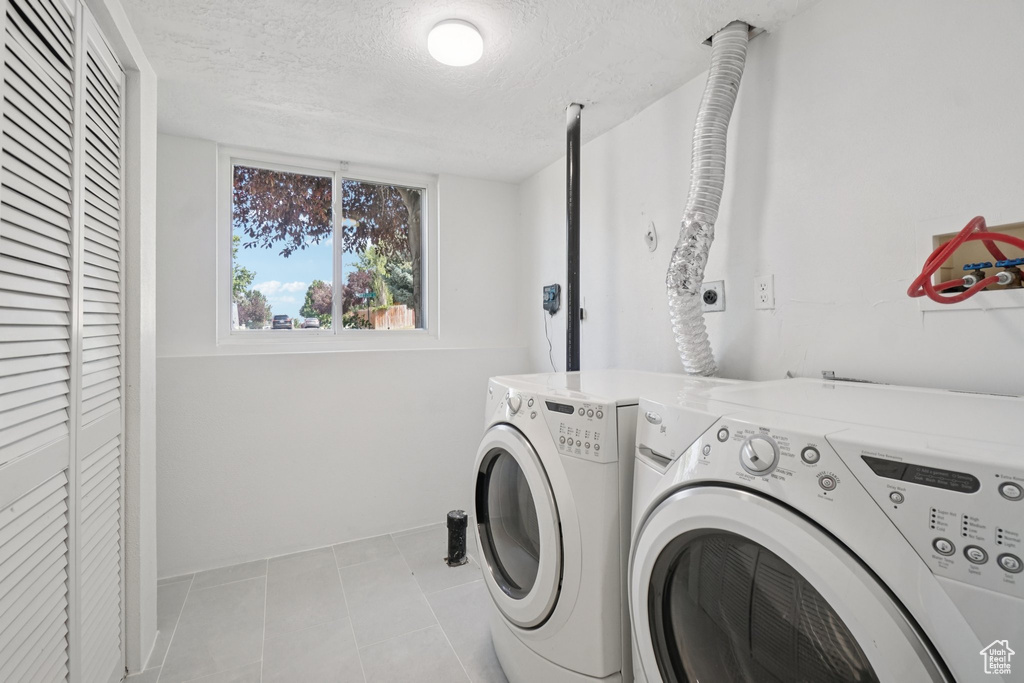 Laundry area with independent washer and dryer, tile patterned flooring, and a textured ceiling