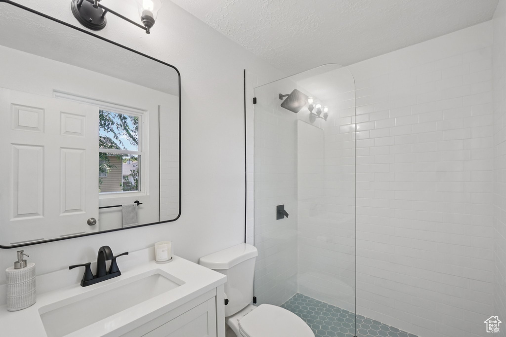 Full bath with vanity, walk in shower, and a textured ceiling