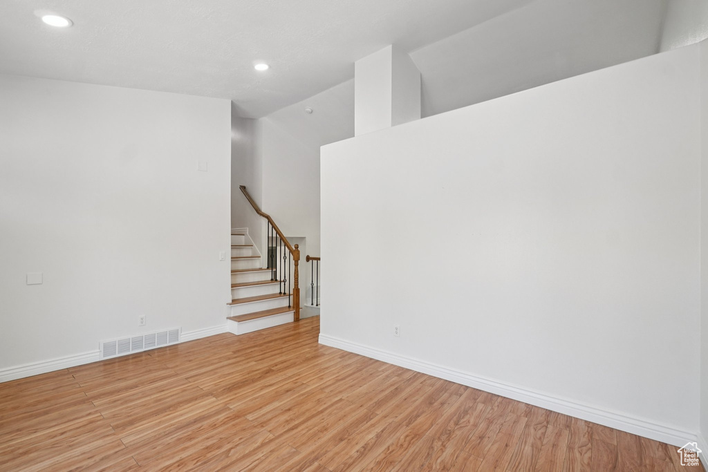 Unfurnished room with light wood finished floors, stairs, recessed lighting, and vaulted ceiling