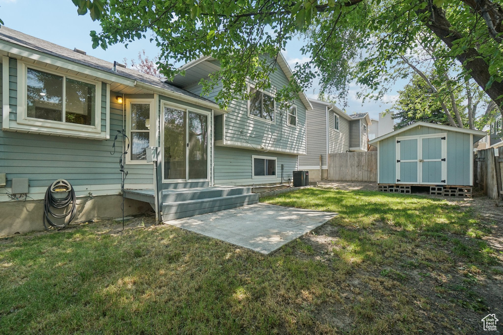 Rear view of property featuring a fenced backyard, entry steps, a storage unit, and a patio