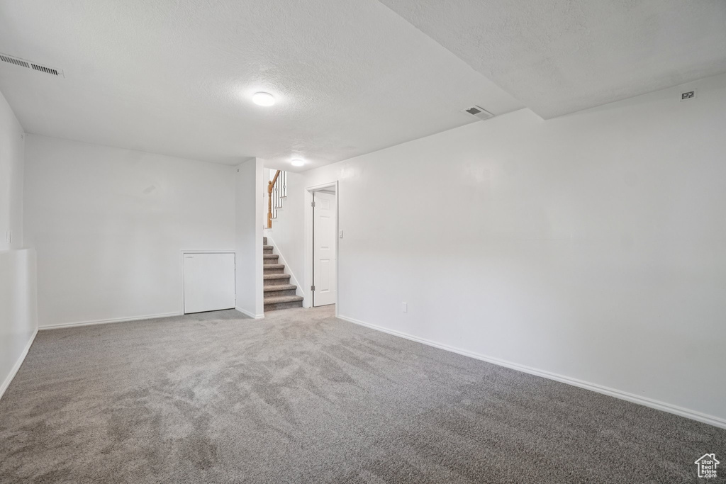 Carpeted empty room with stairway and a textured ceiling