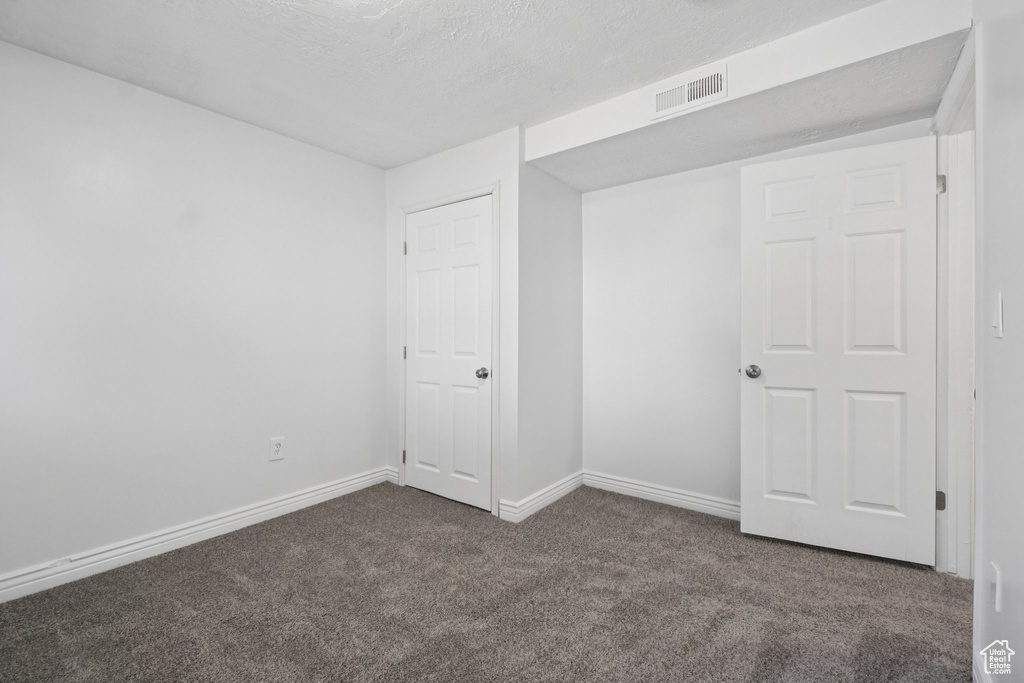 Unfurnished bedroom with carpet floors and a textured ceiling