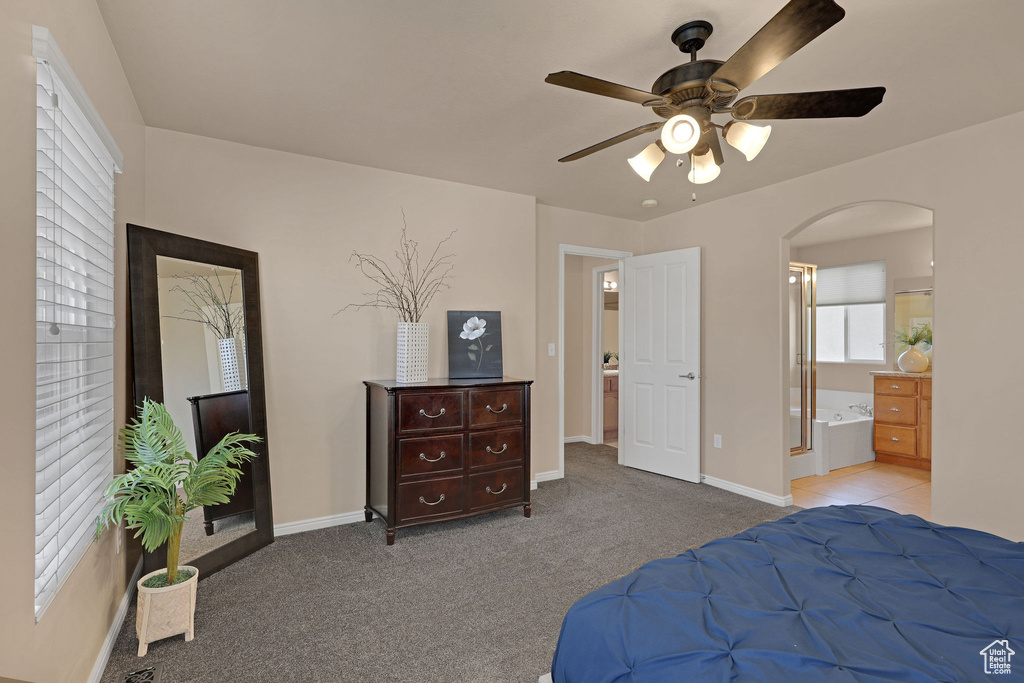 Carpeted bedroom with arched walkways, ensuite bath, and a ceiling fan