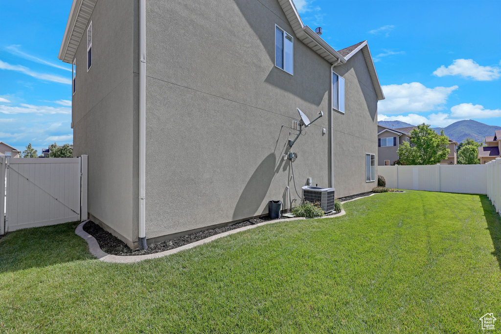 View of side of home featuring a fenced backyard, stucco siding, and a gate