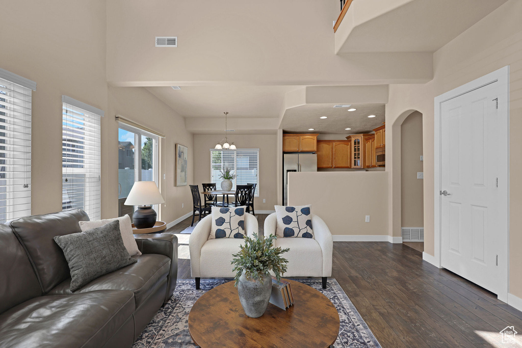 Living area with dark wood-type flooring, arched walkways, a chandelier, and recessed lighting