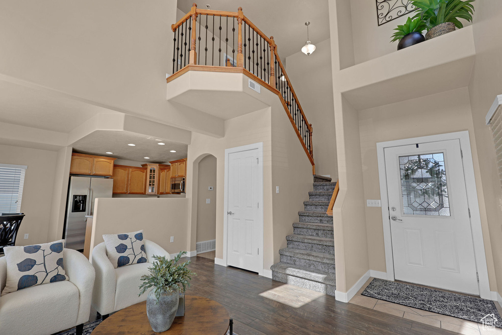 Entrance foyer featuring a high ceiling, wood finished floors, arched walkways, and stairway