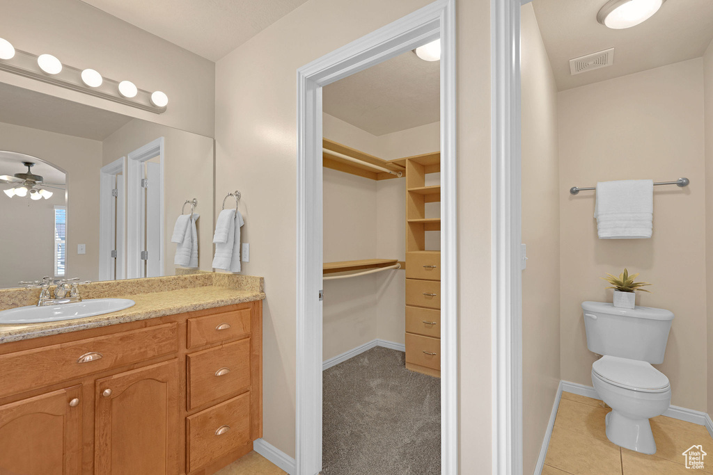 Bathroom featuring vanity, a walk in closet, and ceiling fan
