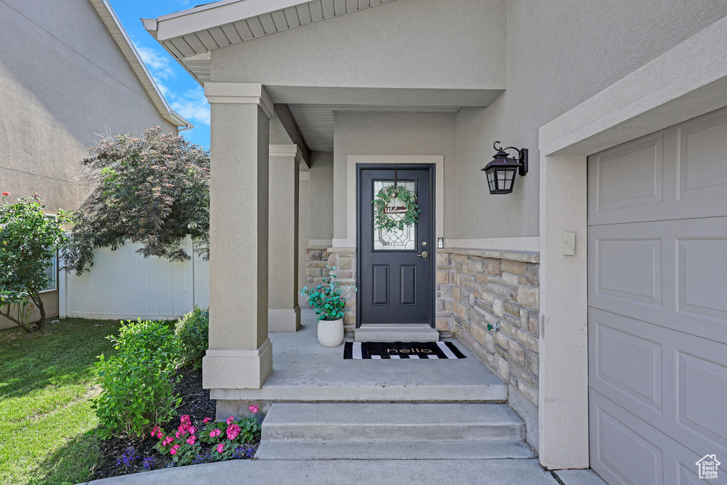 View of exterior entry with stone siding, stucco siding, and a garage