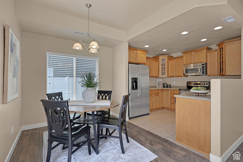Dining space with light wood-type flooring, a chandelier, and recessed lighting