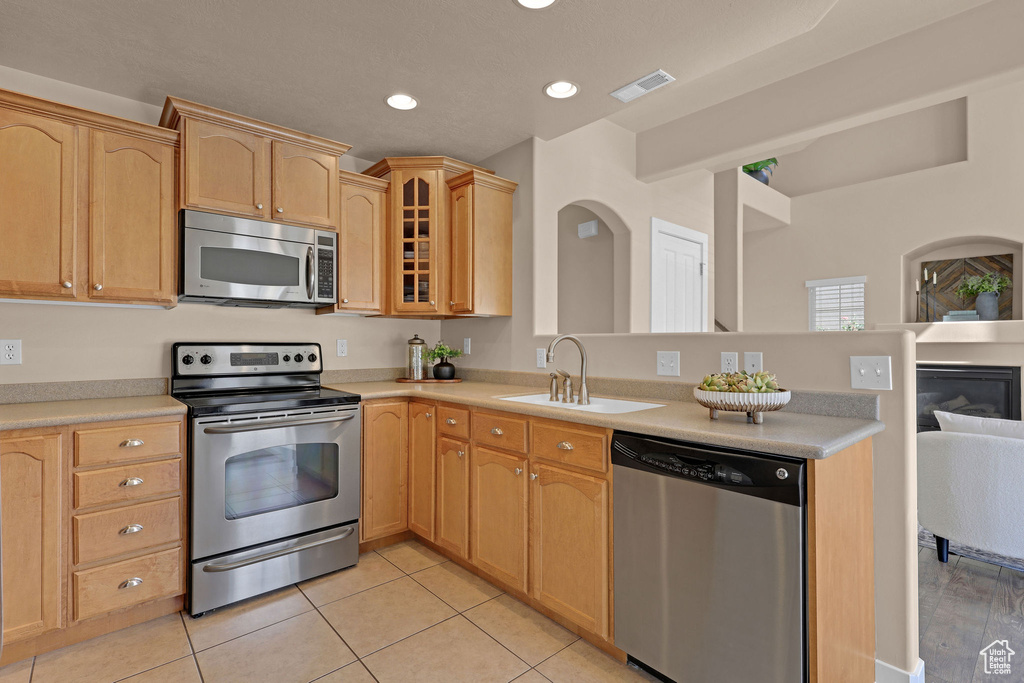 Kitchen with stainless steel appliances, a peninsula, light brown cabinets, recessed lighting, and light countertops