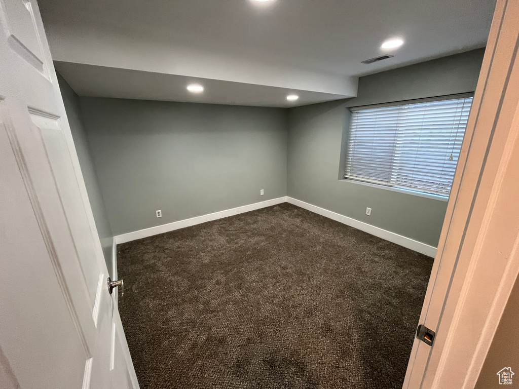 Empty room featuring dark colored carpet and recessed lighting