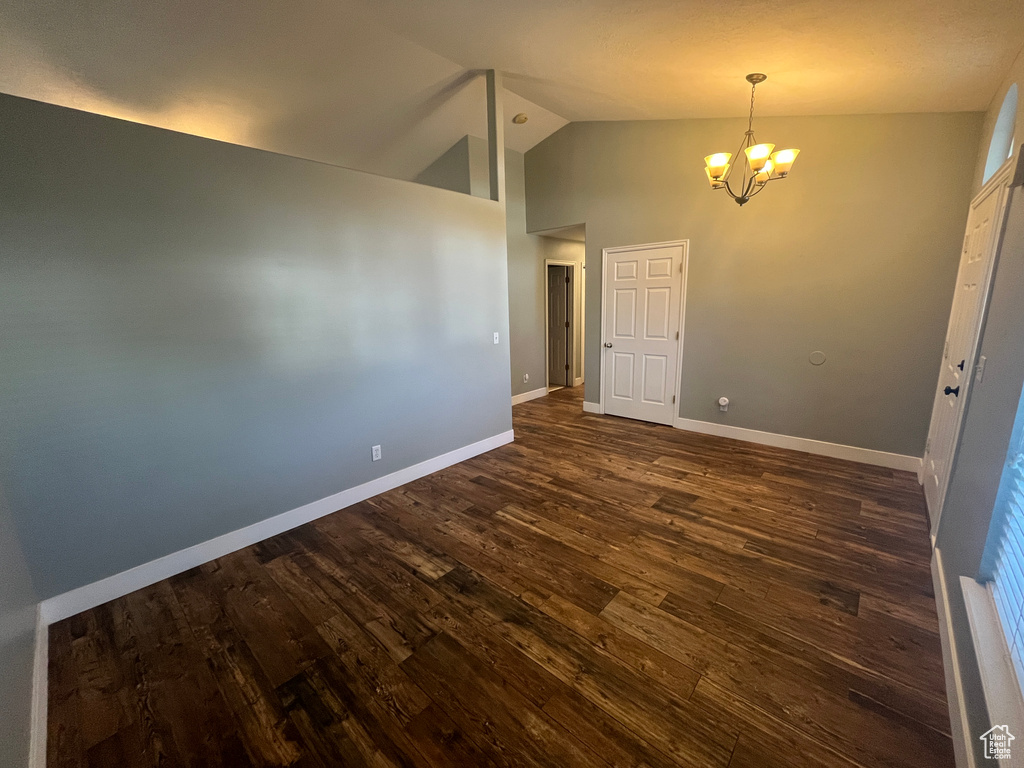 Unfurnished room with a chandelier, dark wood-style flooring, and high vaulted ceiling