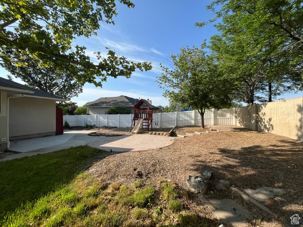 Fenced backyard with a playground and a patio area