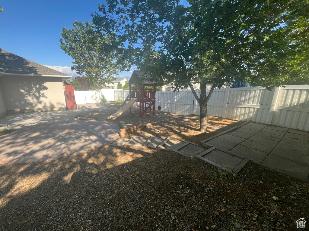 Fenced backyard with a playground and a patio area