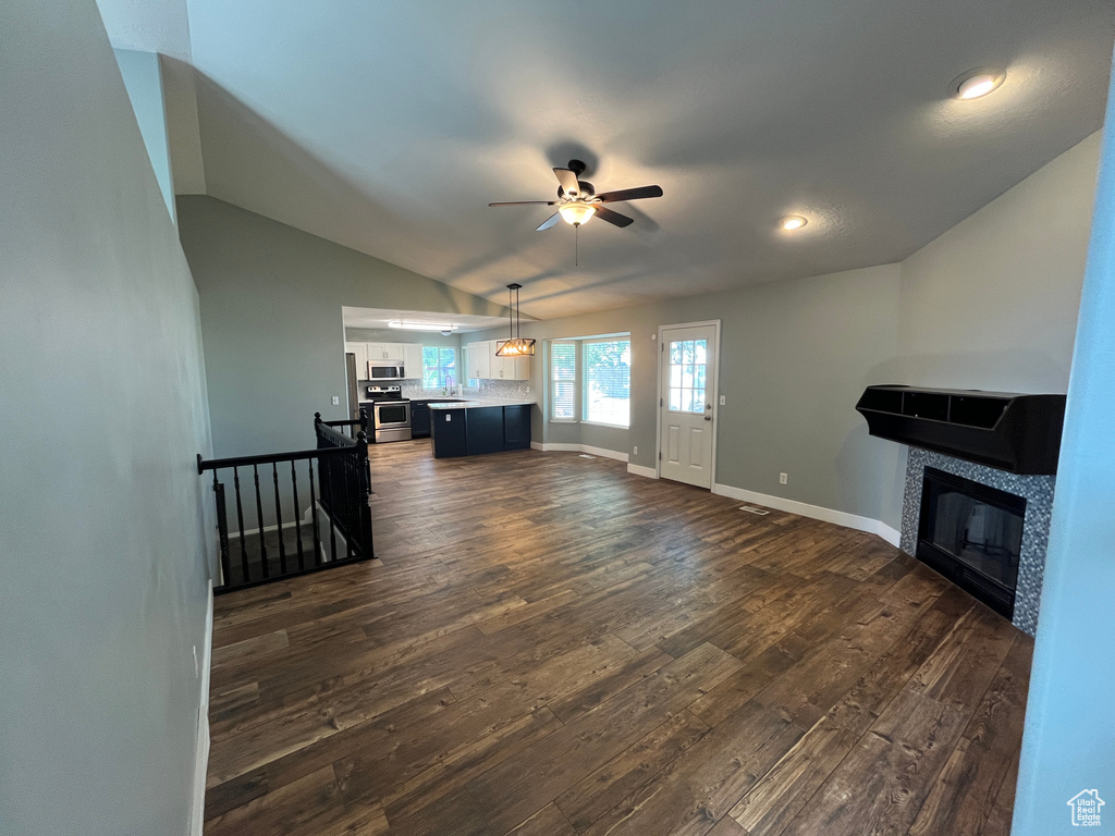 Unfurnished living room with a ceiling fan, dark wood-style flooring, a fireplace, vaulted ceiling, and recessed lighting