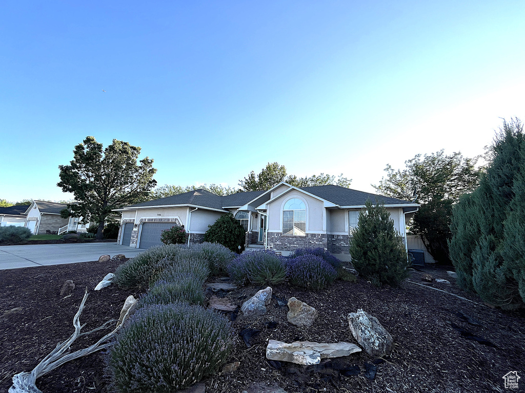 Ranch-style house with an attached garage, stone siding, concrete driveway, and stucco siding