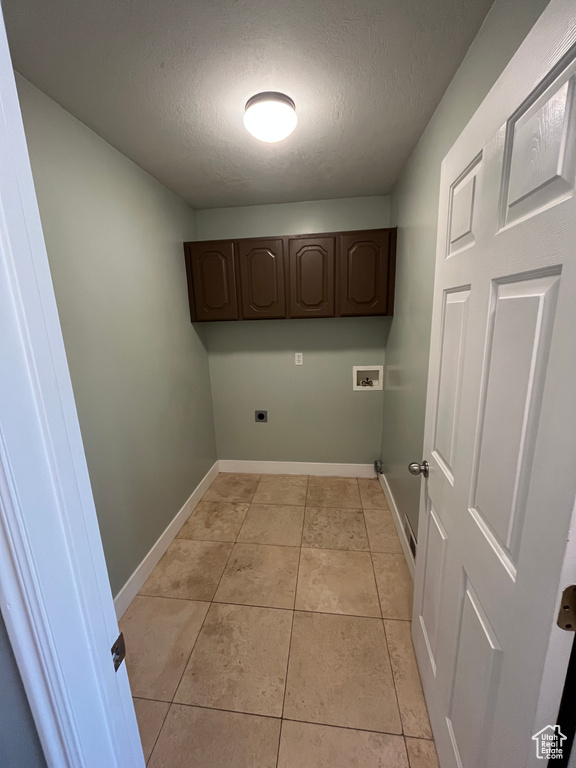 Washroom featuring cabinet space, hookup for a washing machine, hookup for an electric dryer, a textured ceiling, and light tile patterned floors